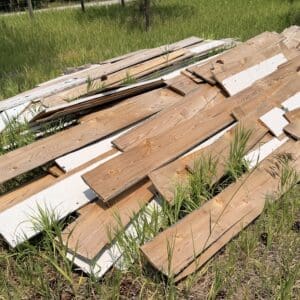IMG_8854 - Montana Auctions by Kevin Hill Piles of weathered wooden boards scattered in a grassy field.