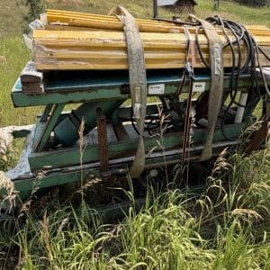 IMG_8922 - Montana Auctions by Kevin Hill Abandoned green farming implement with yellow planks strapped on top in a tall-grass field.