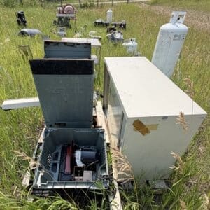 IMG_8941 - Montana Auctions by Kevin Hill Old discarded appliances and propane tanks piled in tall grass in a field west of a rural yard.