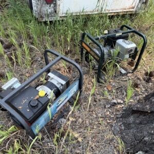 IMG_8974 - Montana Auctions by Kevin Hill Two gas-powered portable generators sit on overgrown grass beside a rusted trailer.
